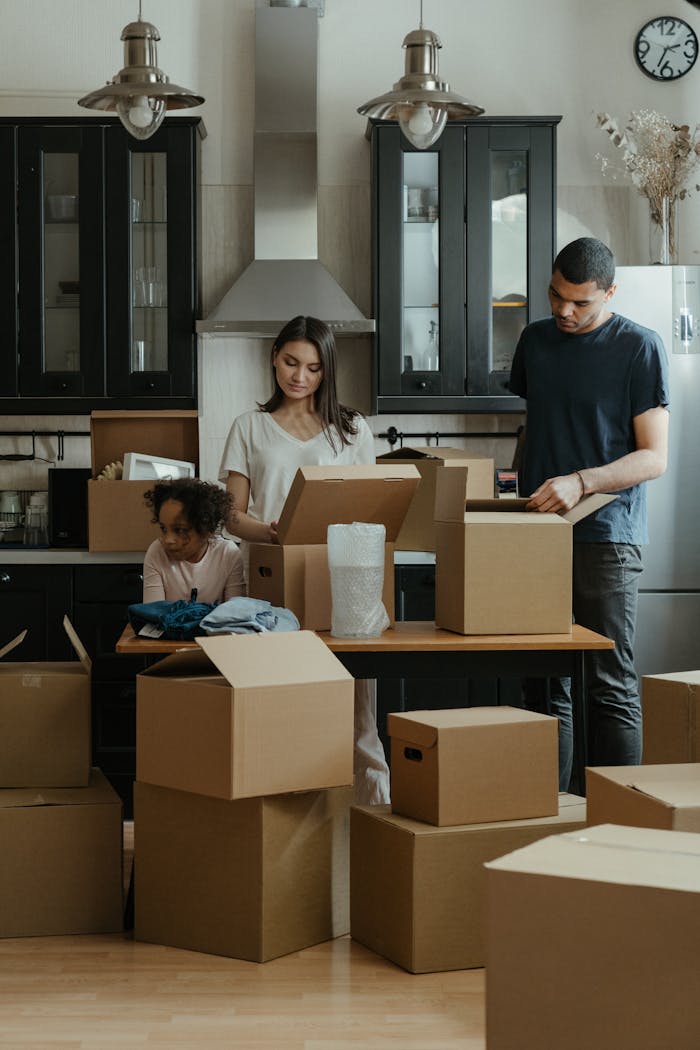 services-img Family unpacking boxes together in a modern kitchen after moving into a new home.